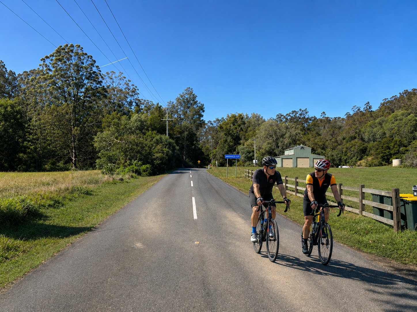 Two cyclists riding along Upper Brookfield Road in Brisbane's western suburbs
